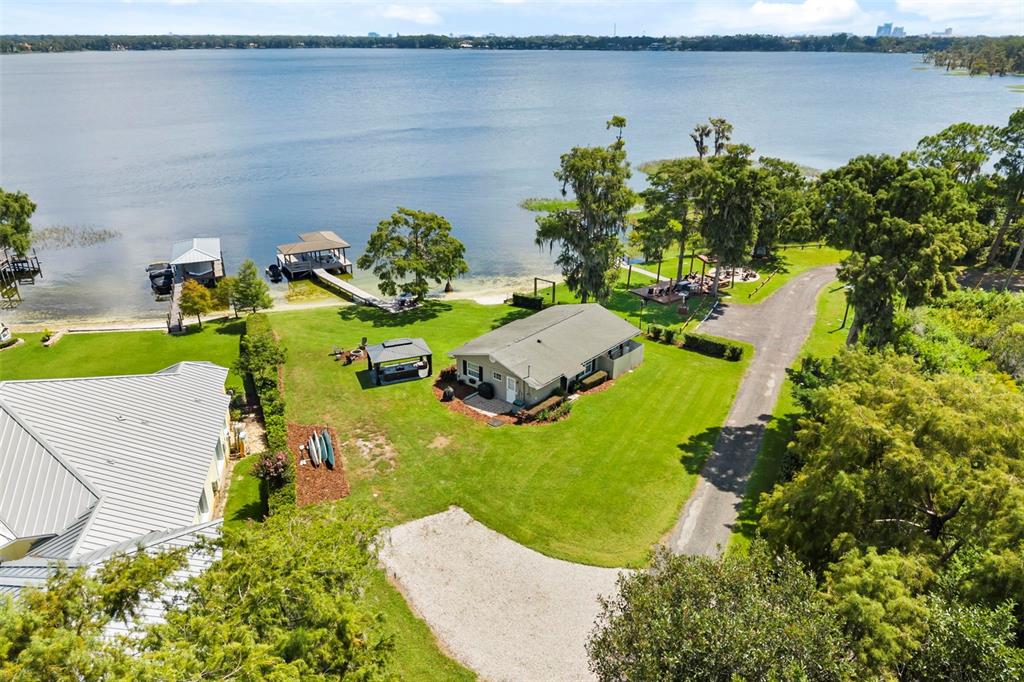 An aerial view shows a house with a lawn, driveway, and private docks on a lake — 10430 LAKE COTTAGE LANE, ORLANDO, FL