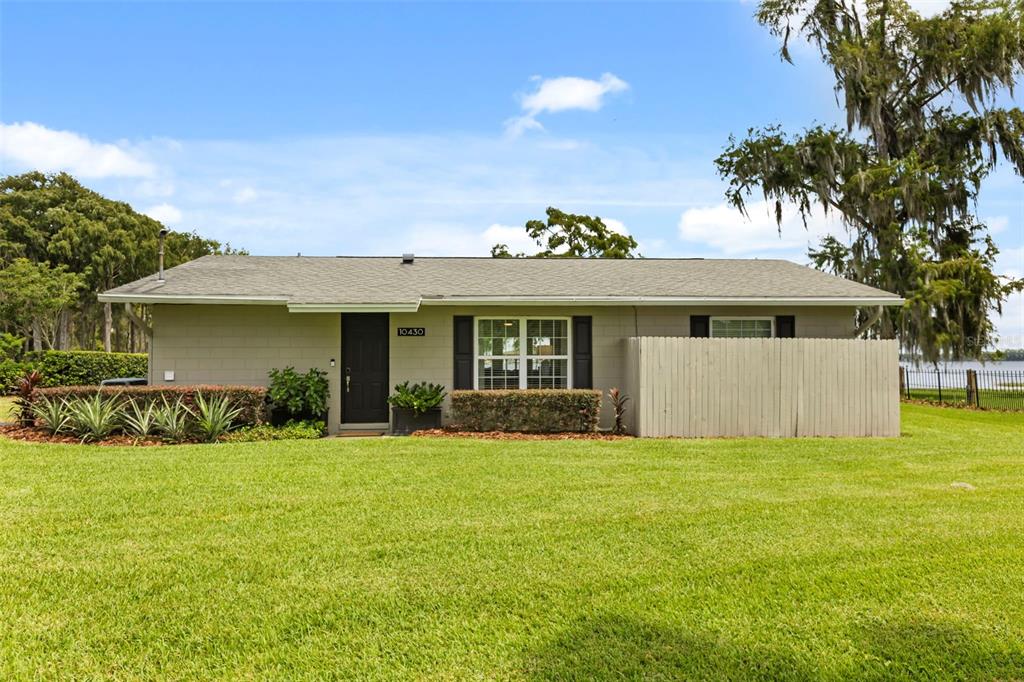 A single-story house with a gray exterior, black shutters, and a wooden privacy fence — 10430 LAKE COTTAGE LANE, ORLANDO, FL