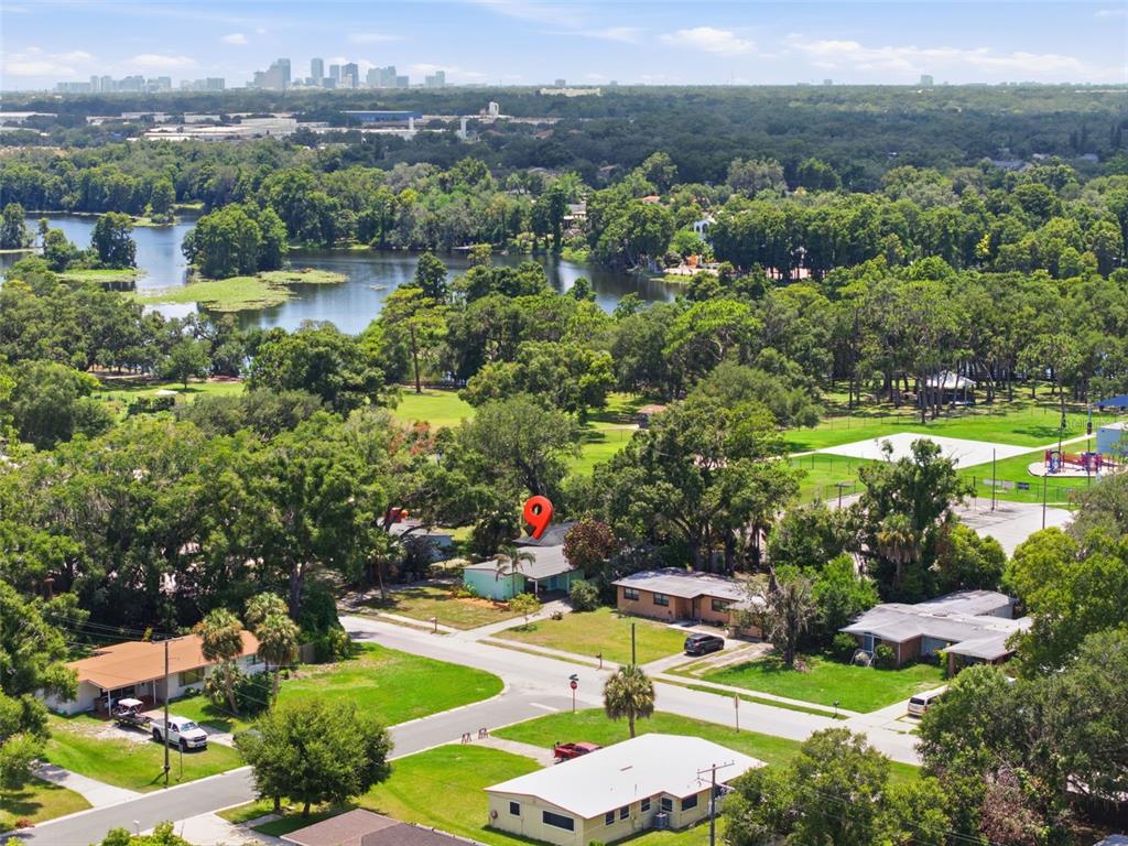 An aerial view shows a residential neighborhood with a lake and a city skyline — 609 W RIVER DRIVE, TEMPLE TERRACE, FL
