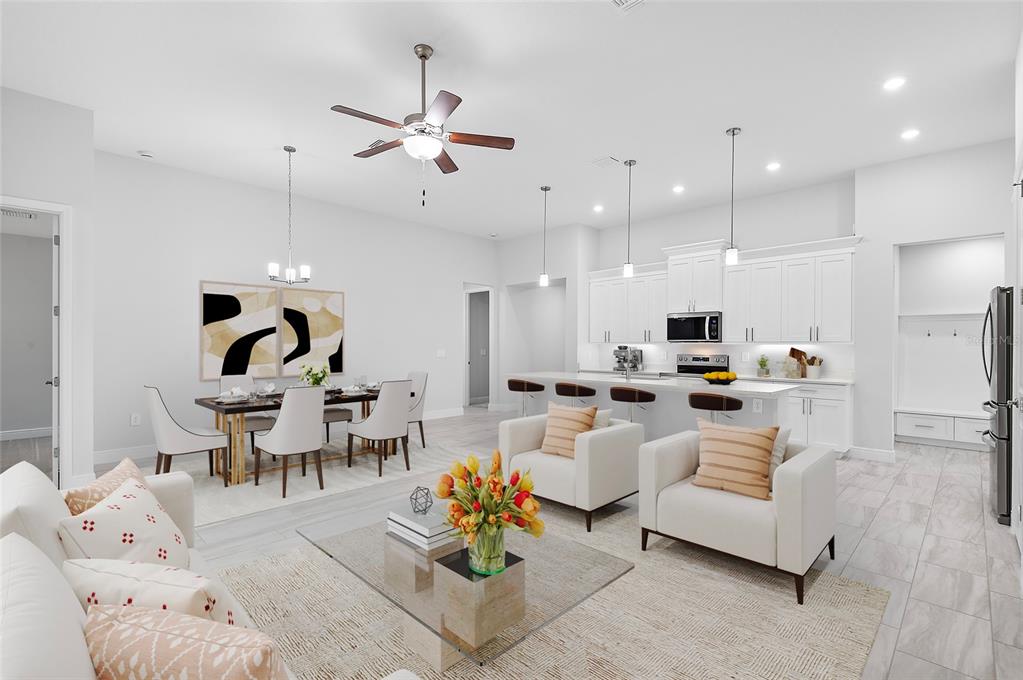 An open-concept living and dining area features white cabinetry, a kitchen island, and tile flooring — 335 MILLER ROAD, SANFORD, FL