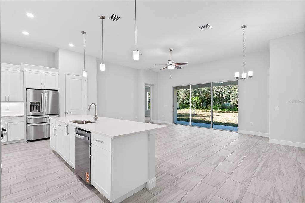 A modern kitchen with a white island and stainless steel appliances opens to a living area — 335 MILLER ROAD, SANFORD, FL