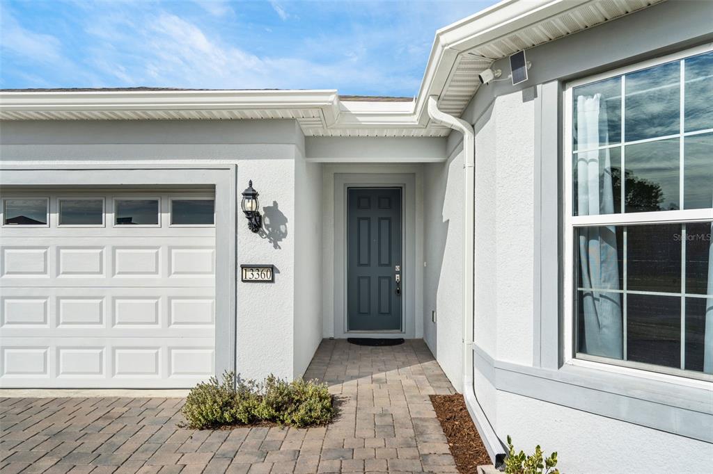 The exterior of a house features a gray front door, a garage, and a walkway — 13360 SUNNY RETREAT LANE, WINTER GARDEN, FL