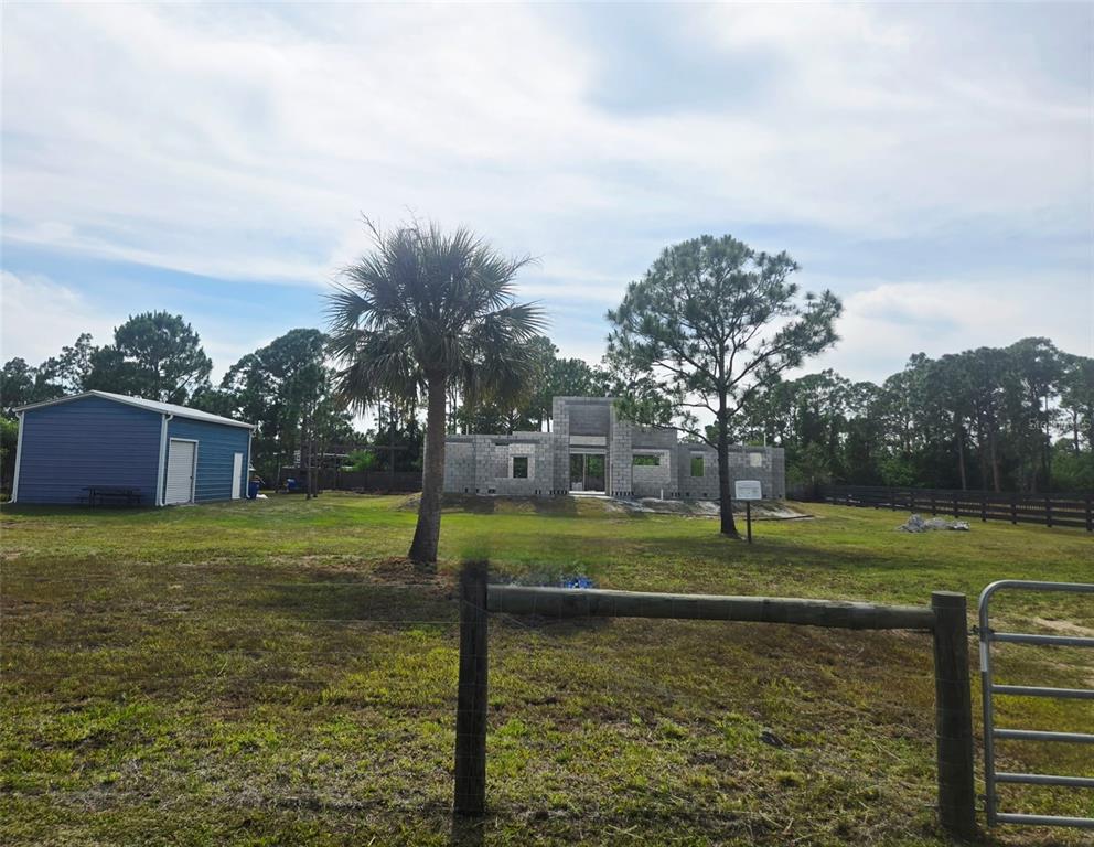 A partially constructed concrete block house stands on a grassy lot with a blue shed — 7441 STRASSE BOULEVARD, PUNTA GORDA, FL