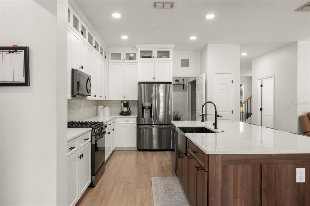 A dining area with wood-look flooring, a dark table, and a black front door — 611 BROOKFIELD TERRACE, DELAND, FL