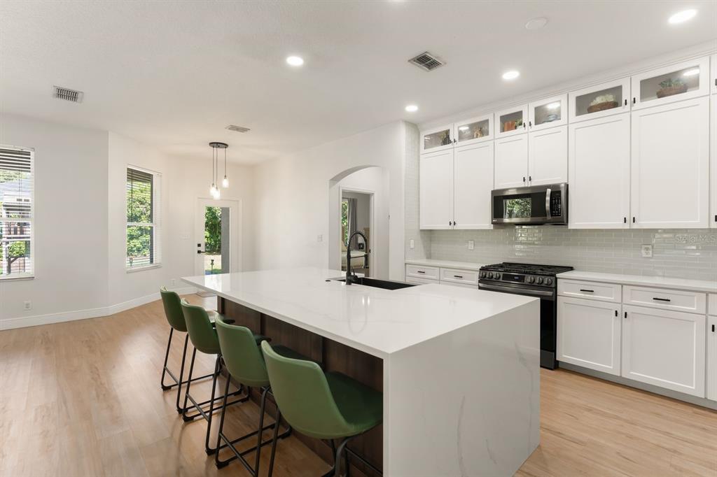 A dining area with light wood-look flooring, a black table set, and a front door — 611 BROOKFIELD TERRACE, DELAND, FL