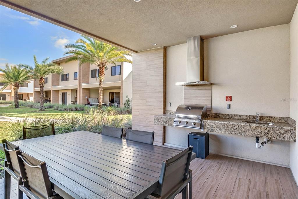 A covered outdoor patio features a dining table, a built-in grill, and a granite countertop — 7540 BROOKLYN DRIVE, KISSIMMEE, FL