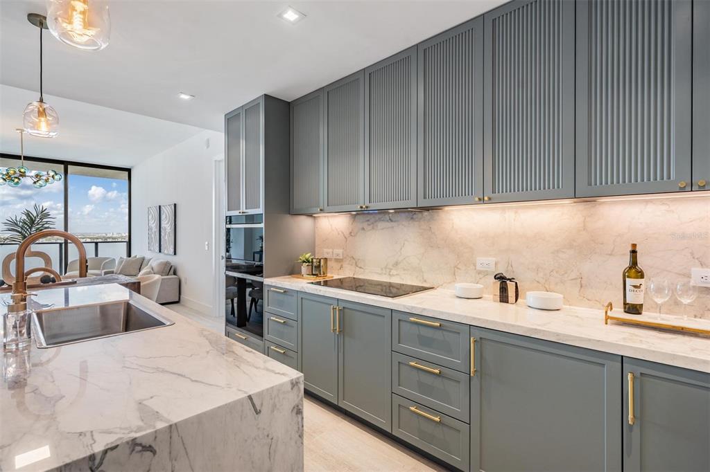 A modern kitchen features a marble waterfall island, sage green cabinetry, and floor-to-ceiling windows — 3015 S YSABELLA AVENUE UNIT 2003, TAMPA, FL