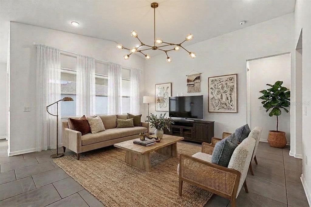 A living room features a beige sofa, two cane chairs, a wood coffee table, and chandelier — 11837 MOONSAIL DRIVE, PARRISH, FL