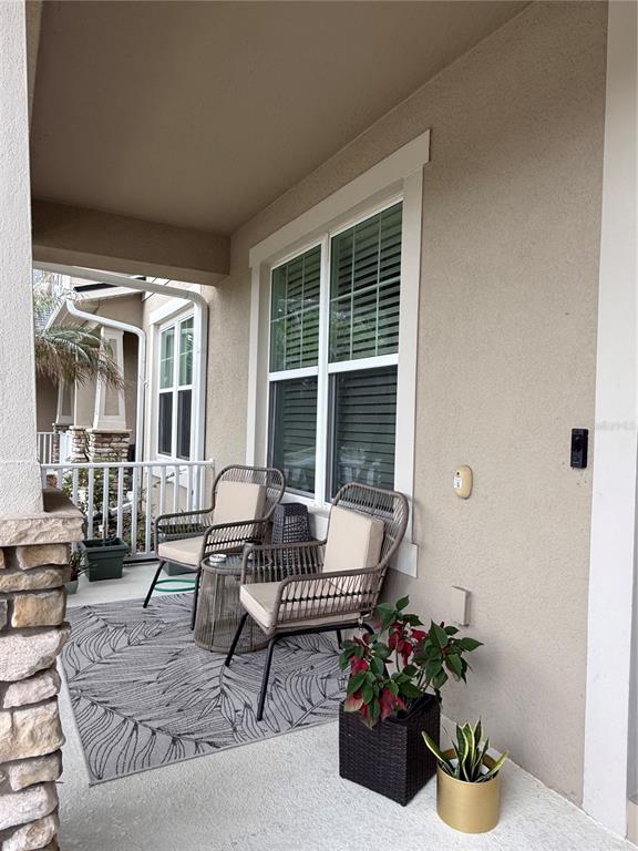 A covered porch features two wicker chairs, a patterned rug, and potted plants — 8386 IRON MOUNTAIN TRAIL, WINDERMERE, FL
