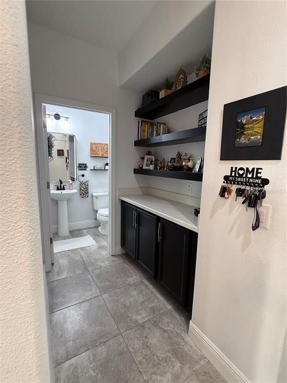 A hallway features black cabinets, floating shelves, and an entryway into a small bathroom — 8386 IRON MOUNTAIN TRAIL, WINDERMERE, FL