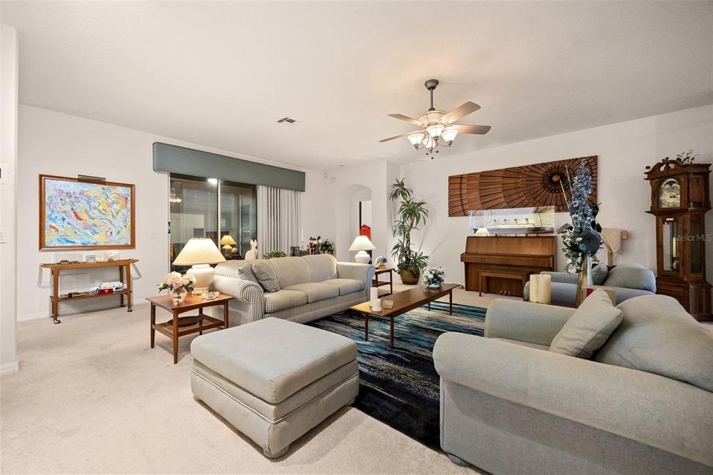 A living room features light-colored furniture, a blue area rug, a piano, and a grandfather clock — 4122 KINGSLEY STREET, CLERMONT, FL