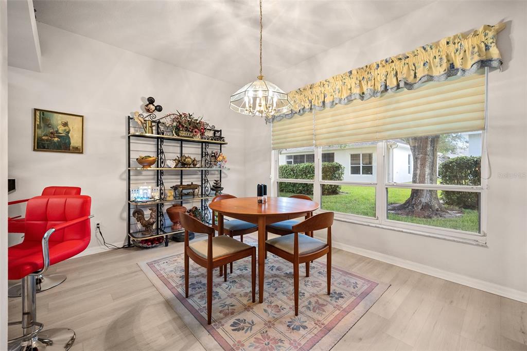 A kitchen features white cabinets, black countertops, a mosaic tile backsplash, and light wood flooring — 4122 KINGSLEY STREET, CLERMONT, FL