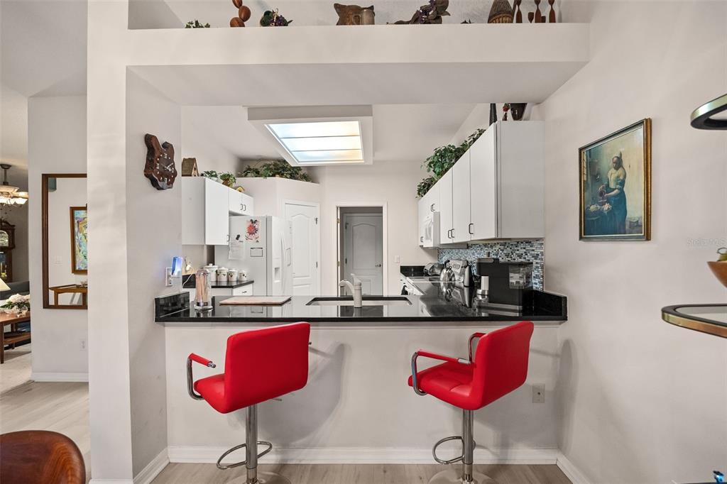 A kitchen with white cabinets, black countertops, and a view into the dining area — 4122 KINGSLEY STREET, CLERMONT, FL