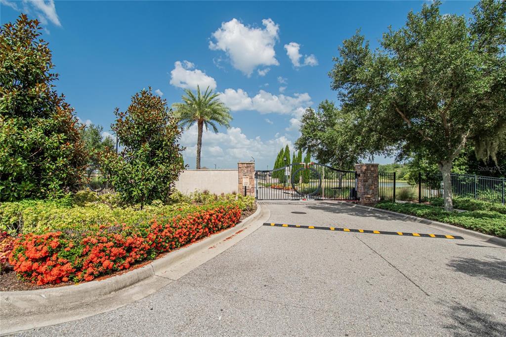 A paved road leads to a gated entrance surrounded by lush landscaping and mature trees — 16441 TREASURE POINT DRIVE, WIMAUMA, FL