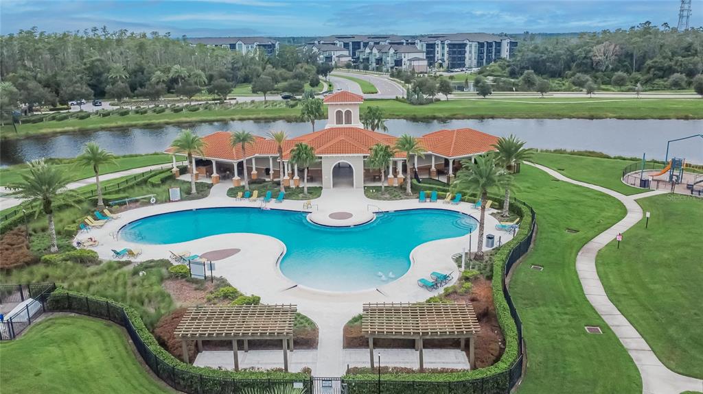An aerial view of a community swimming pool with a clubhouse and surrounding green space — 16441 TREASURE POINT DRIVE, WIMAUMA, FL