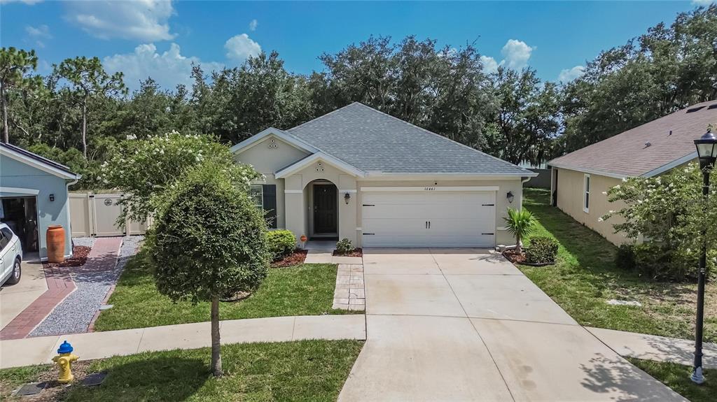A single-story house with a beige stucco exterior, a two-car garage, and a concrete driveway — 16441 TREASURE POINT DRIVE, WIMAUMA, FL