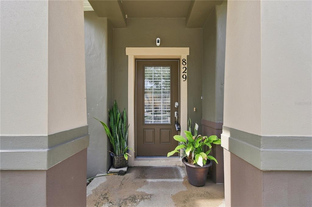The front entrance features a brown door with a glass insert and two potted plants — 829 BELLES FERRY LOOP, SANFORD, FL