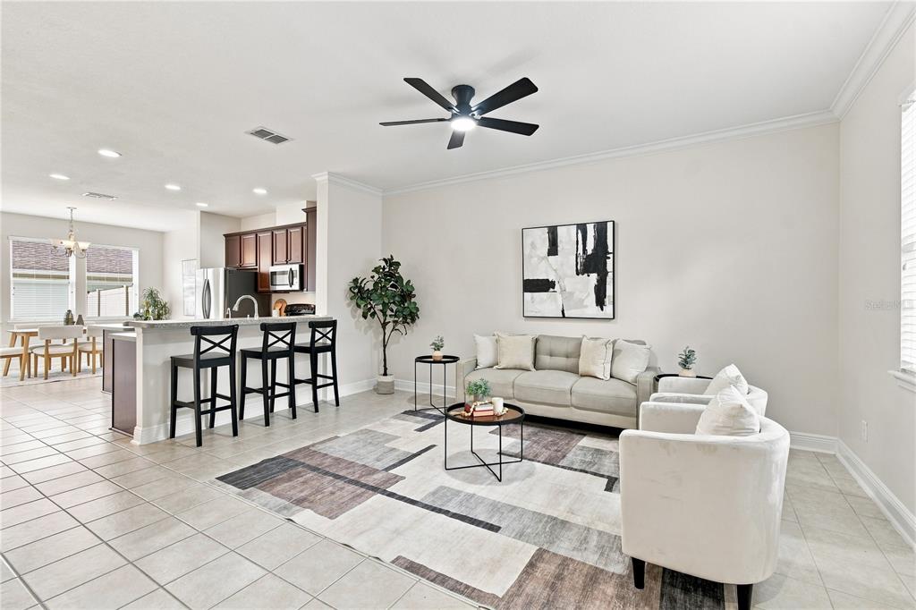 A living room with a grey sofa, two armchairs, and a kitchen island with bar stools — 829 BELLES FERRY LOOP, SANFORD, FL