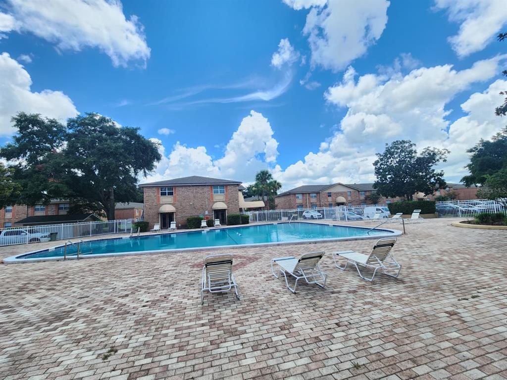 A rectangular swimming pool is surrounded by a brick patio and lounge chairs — 416 BANYON TREE CIRCLE UNIT 108, MAITLAND, FL