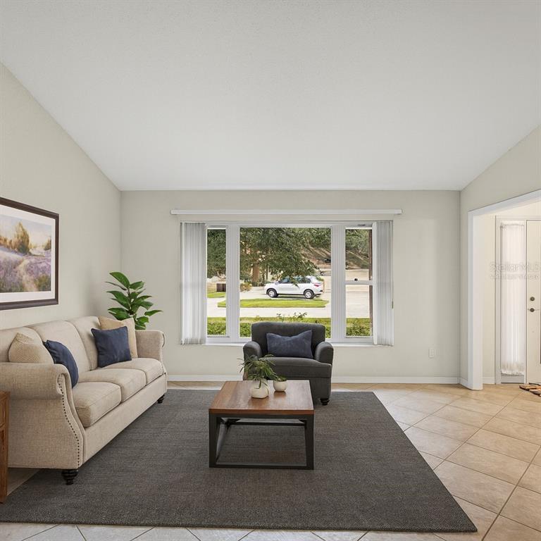 A living room features a beige sofa, a dark armchair, a coffee table, and large windows — 12595 93RD WAY, LARGO, FL