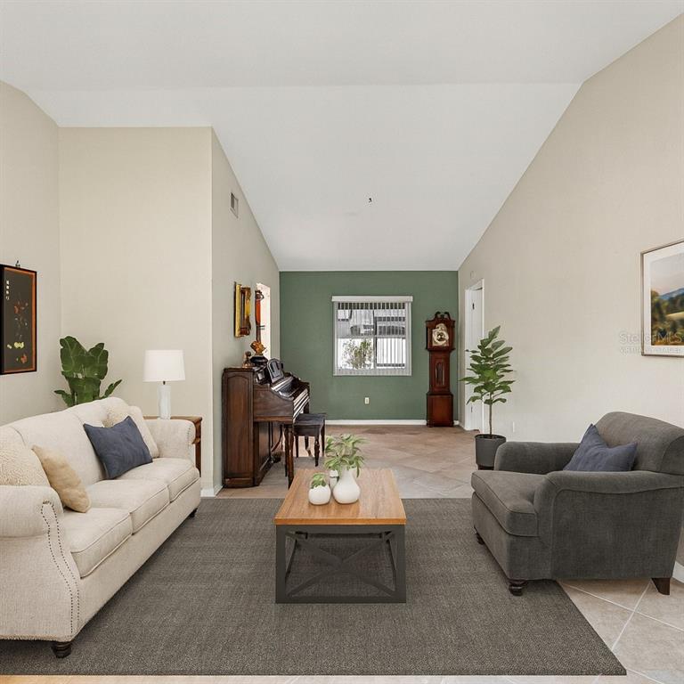 A living room features a beige sofa, gray armchair, wooden coffee table, and upright piano — 12595 93RD WAY, LARGO, FL