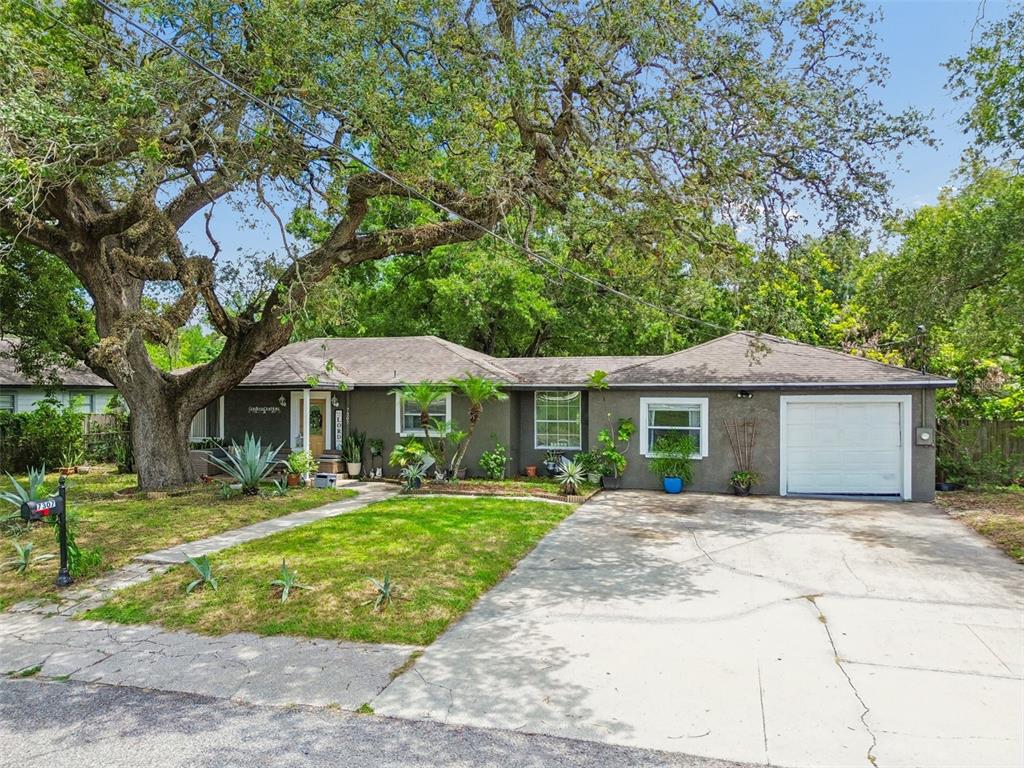 A single-story gray house with a garage and a large oak tree in the yard — 7307 N HUNTLEY AVENUE, TAMPA, FL