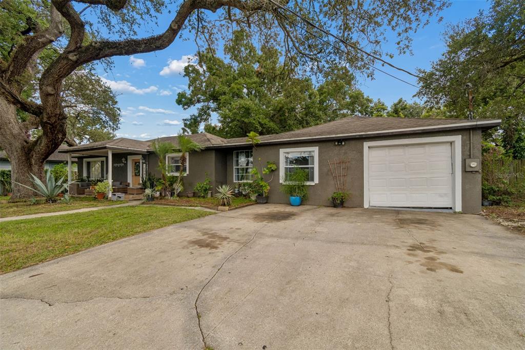 A single-story house with a gray stucco exterior, a front porch, and an attached garage — 7307 N HUNTLEY AVENUE, TAMPA, FL