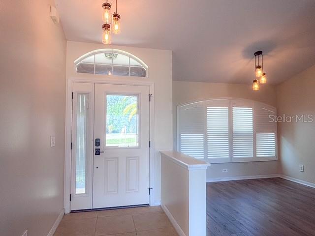 An entryway features a white front door with a transom window and wood-look flooring — 309 GENTLE BREEZE DRIVE, MINNEOLA, FL
