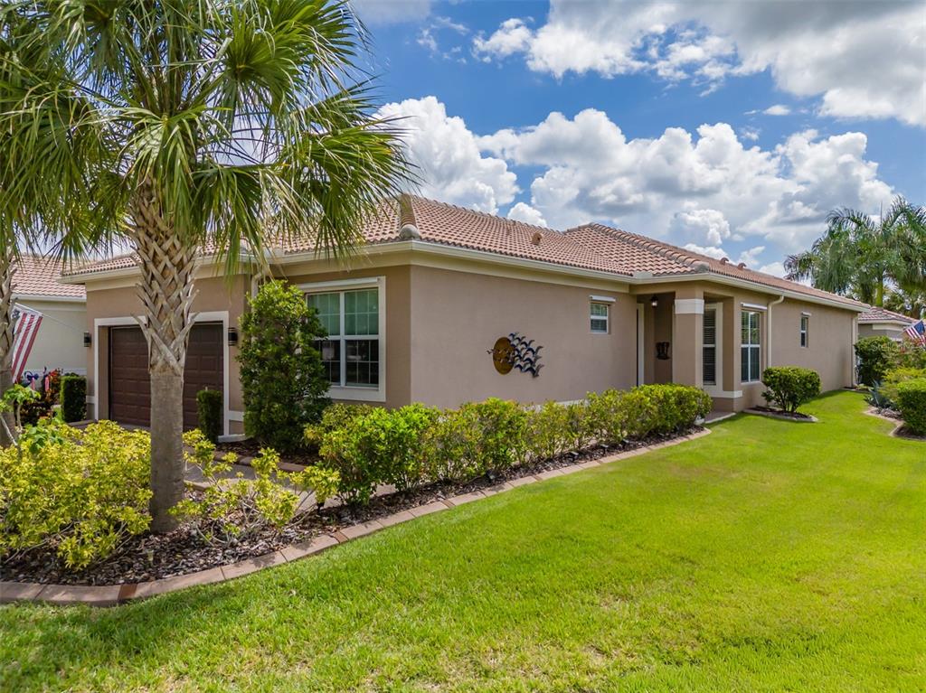 A tan stucco house with a tiled roof, a palm tree, and a manicured lawn — 4905 SANDY GLEN WAY, WIMAUMA, FL