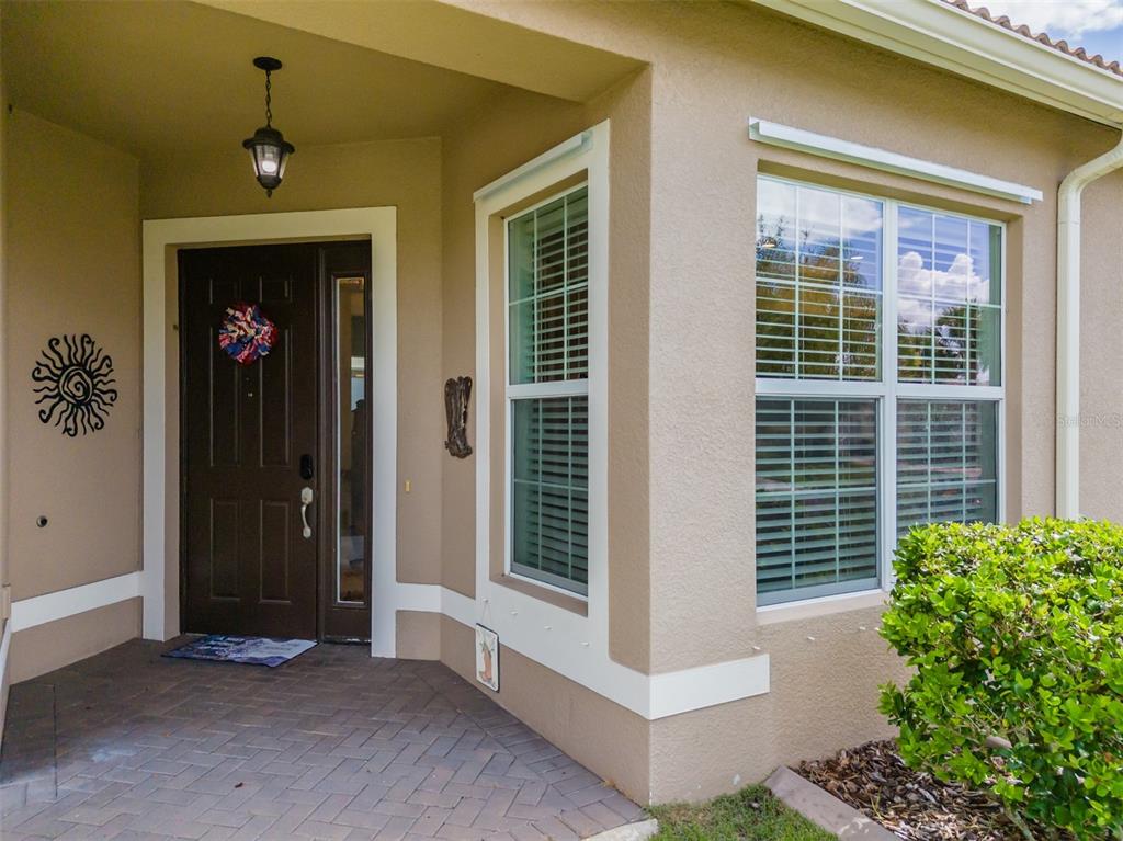 A front entryway features a dark brown door, a brick porch, and two windows with shutters — 4905 SANDY GLEN WAY, WIMAUMA, FL
