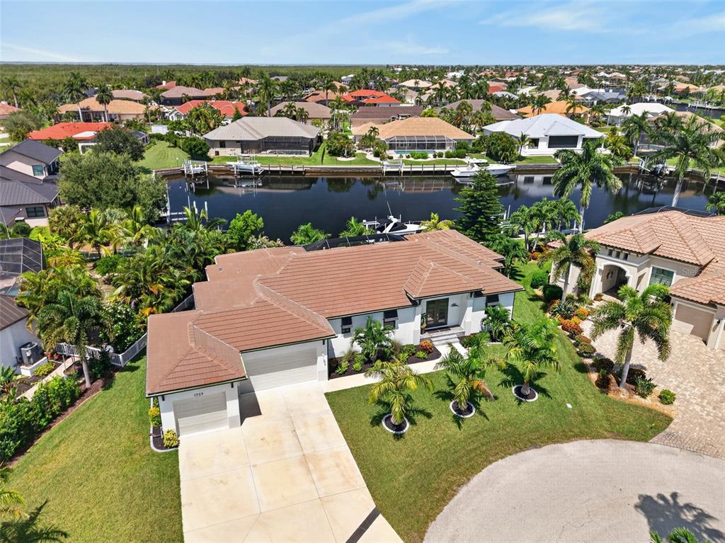 An aerial view shows a house with a brown tile roof, white walls, and a canal — 1737 CASEY KEY DRIVE, PUNTA GORDA, FL