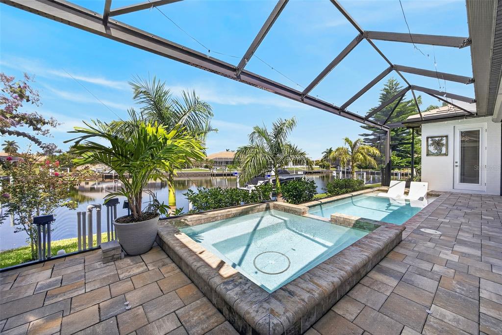 A screened-in patio features a raised spa and a small pool overlooking a canal — 1737 CASEY KEY DRIVE, PUNTA GORDA, FL