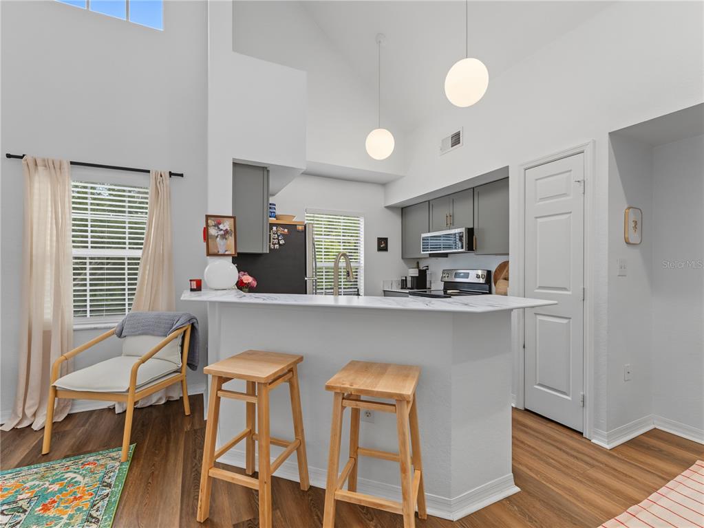 A kitchen with gray cabinets, a white marble-look breakfast bar, and two wooden stools — 9186 LAKE CHASE ISLAND WAY, TAMPA, FL