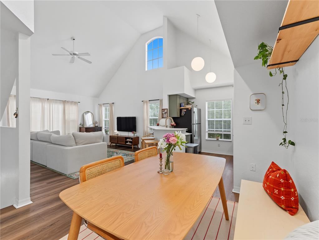 A dining area with a wooden table leads into a living room with vaulted ceilings — 9186 LAKE CHASE ISLAND WAY, TAMPA, FL