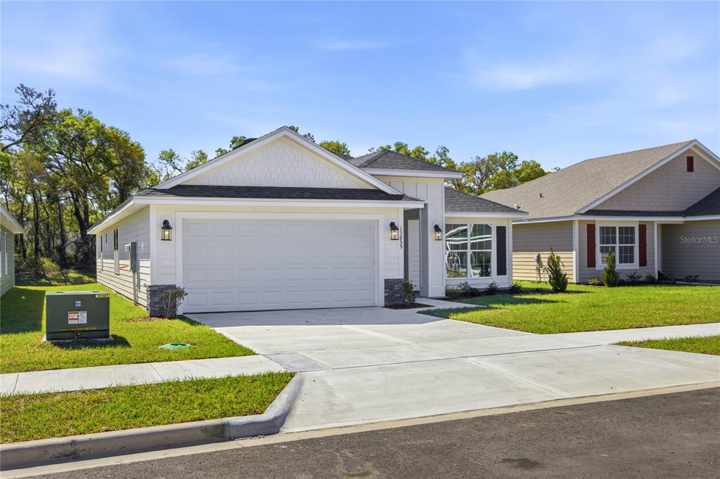A single-story house with a white garage, light siding, and a concrete driveway — 2590 SW 250TH TERRACE, NEWBERRY, FL