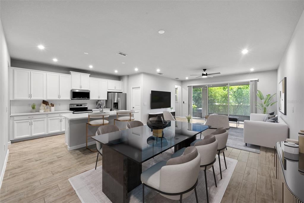 An open-concept living area features a modern kitchen, dining table, and a bright living room — 4366 CLOUD HOPPER WAY, LUTZ, FL