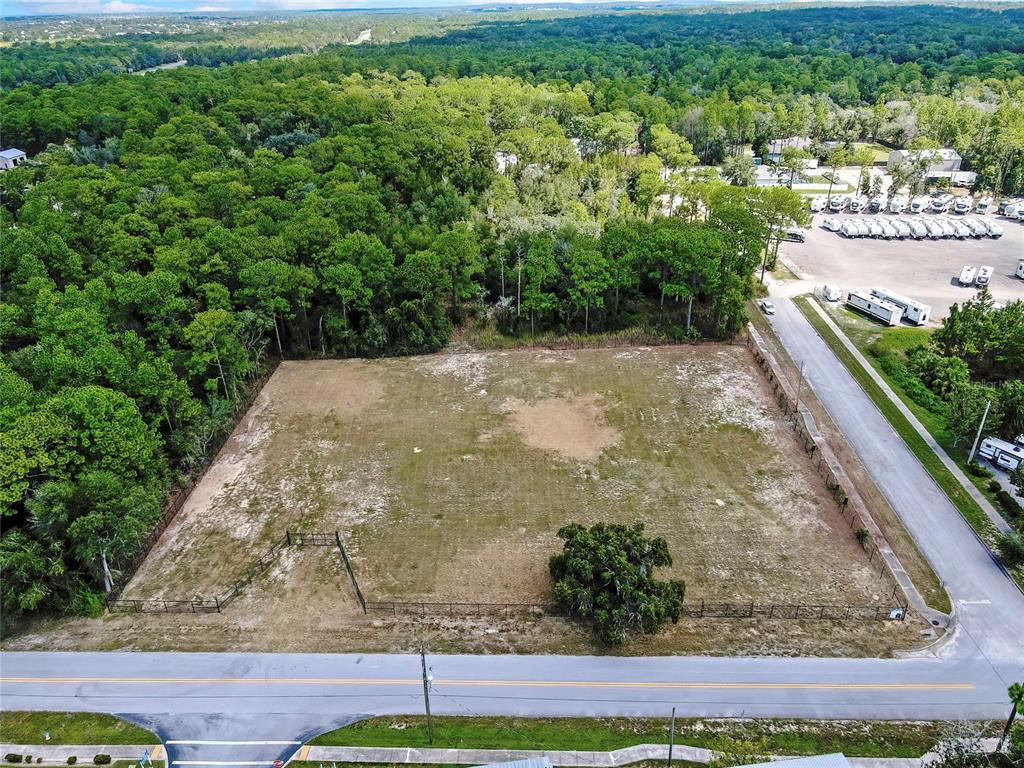 An aerial view shows a rectangular, cleared vacant lot bordered by trees and a road — 15241 HORN AVENUE, BROOKSVILLE, FL