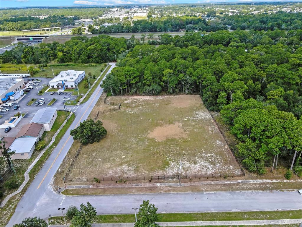 An aerial view shows a vacant, fenced rectangular lot bordered by a road and trees — 15241 HORN AVENUE, BROOKSVILLE, FL