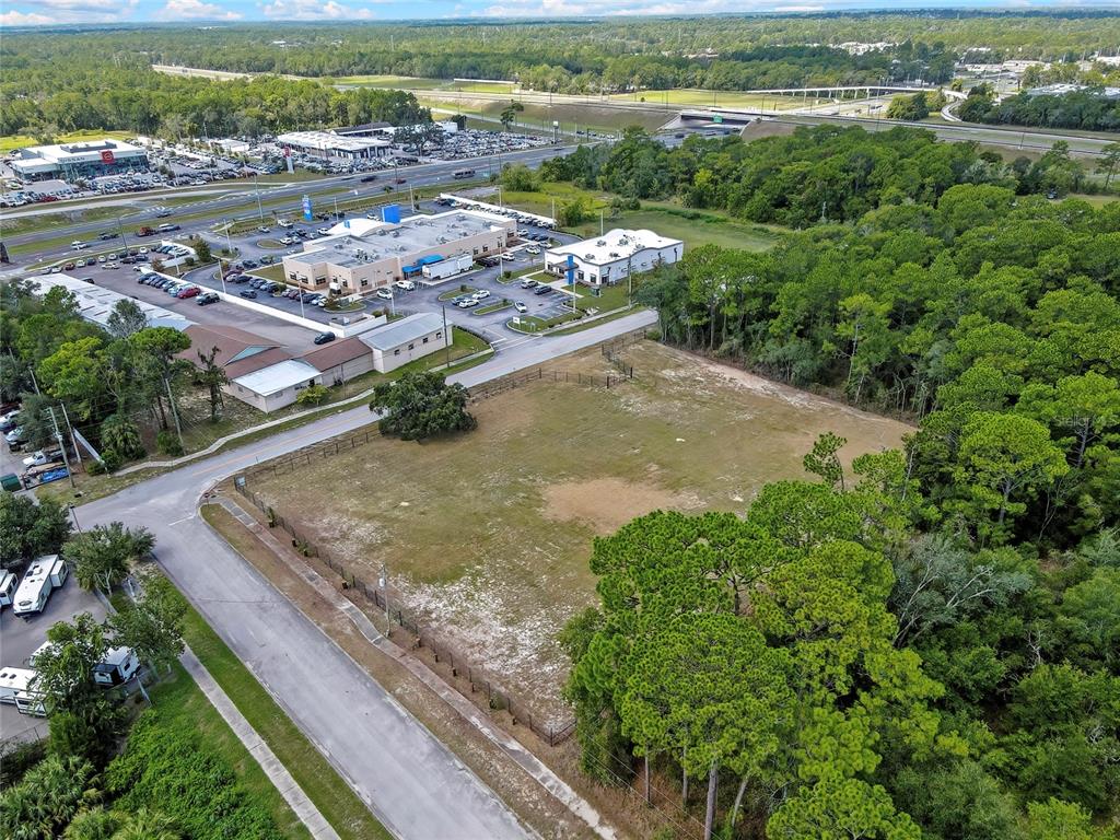 An aerial view shows a vacant, fenced rectangular lot bordered by a road and trees — 15241 HORN AVENUE, BROOKSVILLE, FL