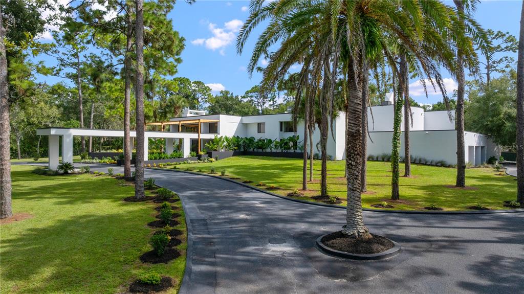 A modern white house with a long driveway and palm trees sits on a grassy lot — 808 SWEETWATER CLUB BOULEVARD, LONGWOOD, FL
