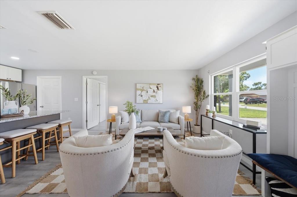 A living room features a checkered rug, two cream armchairs, a sofa, and kitchen seating — 3568 4TH AVENUE SE, LARGO, FL