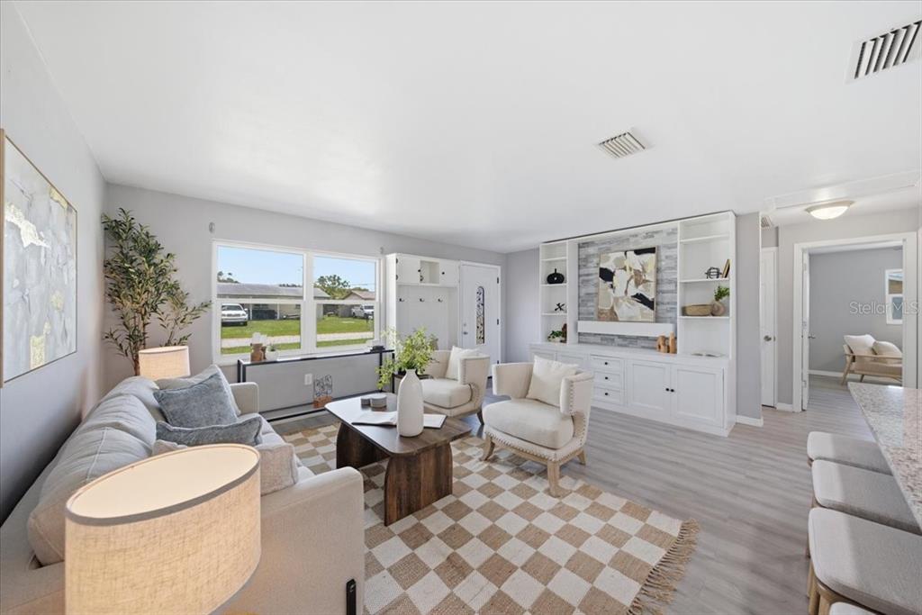 A living room features a light-colored sofa, two armchairs, a checkered rug, and built-in shelving — 3568 4TH AVENUE SE, LARGO, FL