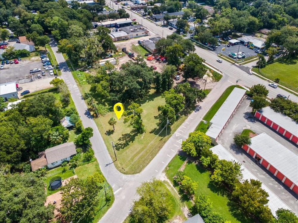 An aerial view shows a vacant, tree-covered lot marked by a yellow pin — 919 TOMOKA RD, DAYTONA BEACH, FL