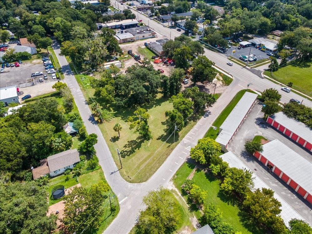An aerial view shows a vacant, tree-covered lot situated between two paved roads — 919 TOMOKA RD, DAYTONA BEACH, FL