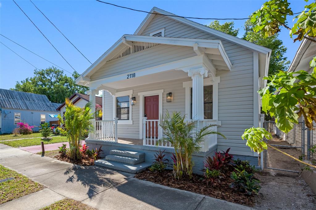 A light gray, single-story house with a front porch, white columns, and a red door — 2118 W PALMETTO STREET, TAMPA, FL