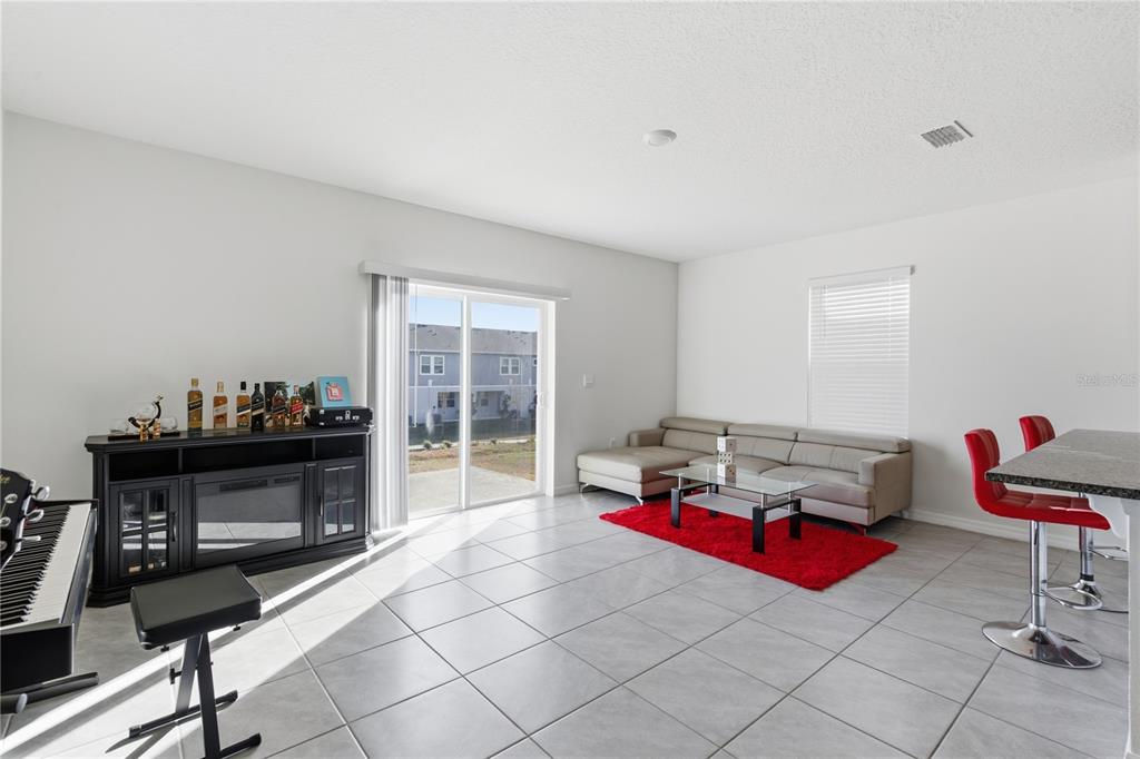 A living room features light tile flooring, a grey sectional sofa, and a black media console — 1727 WOODEN STREET, DAVENPORT, FL