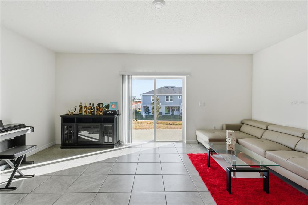 A living room with tile floors, a beige sectional sofa, a red rug, and sliding doors — 1727 WOODEN STREET, DAVENPORT, FL