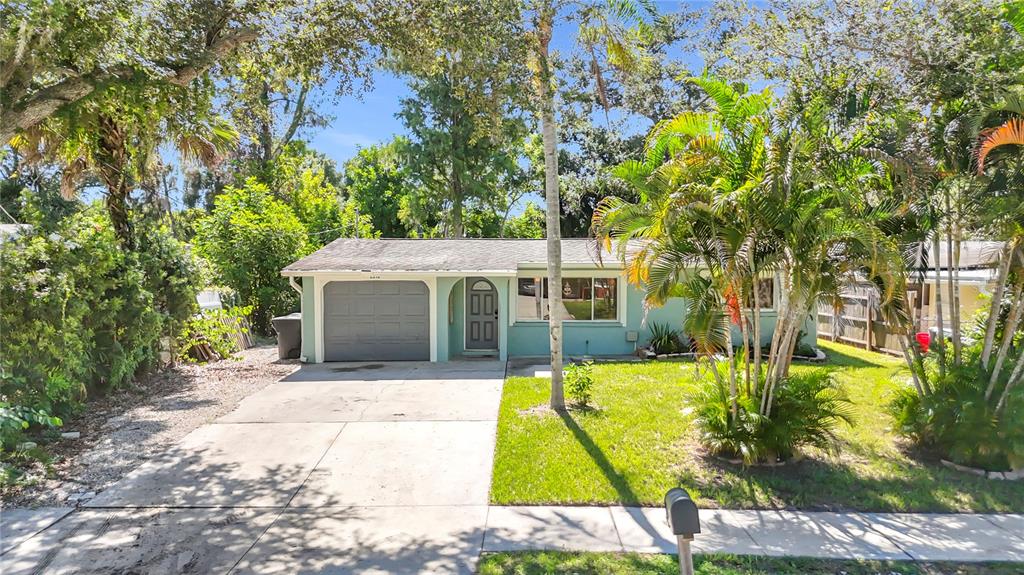 A single-story house with a light blue exterior, a gray garage door, and palm trees — 2212 VINSON AVENUE, SARASOTA, FL