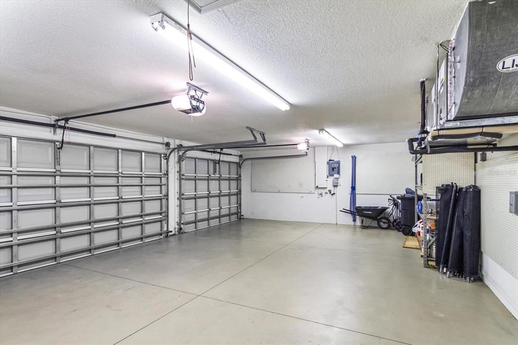 A spacious two-car garage with concrete floors, white walls, and overhead lighting — 144 PARK TRACE BOULEVARD, OSPREY, FL