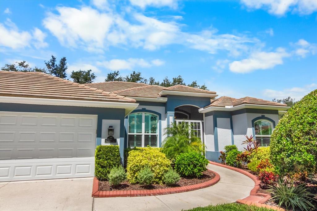 A single-story house with a white garage, blue trim, and a curved brick-bordered walkway — 144 PARK TRACE BOULEVARD, OSPREY, FL